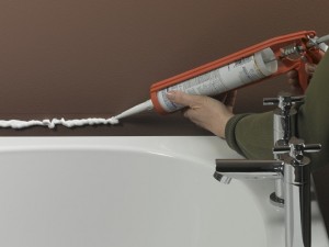 Applying silicone sealant to position bath