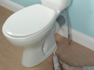 applying silicone sealant around the base of the toilet pan