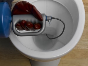 Pushing auger into toilet U-bend